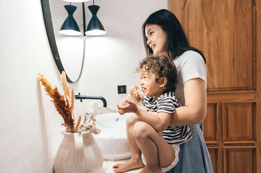 Happy Chinese mother and son  at home brushing their teeth in the bathroom - lifestyle concepts