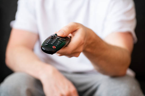 istock Man pointing with a tv remote and pushing buttons 1964946758