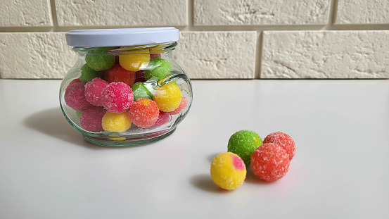 Colorful candies in a jar on a table on a white background