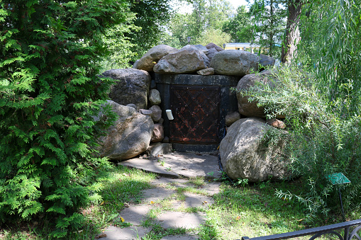 Forged small closed doors to a stone cave, decor in the park.
