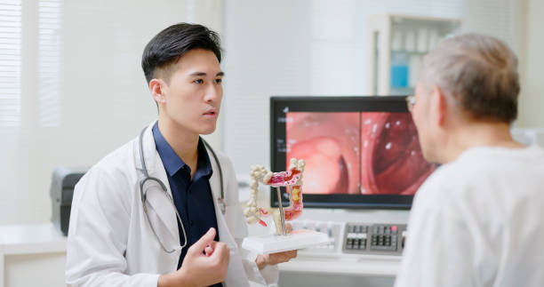 doctor explain tumor surgery asian male doctor is explaining colonoscopy tumor surgery result to elderly man through computer screen and colon model colon stock pictures, royalty-free photos & images
