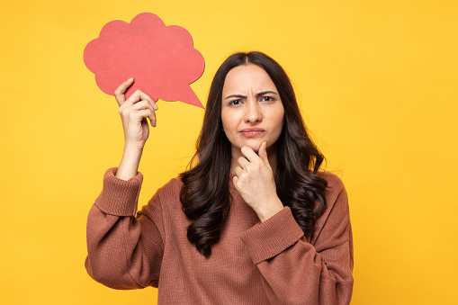 Photo of young woman in winter wear holding bubble of thoughts isolated yellow background