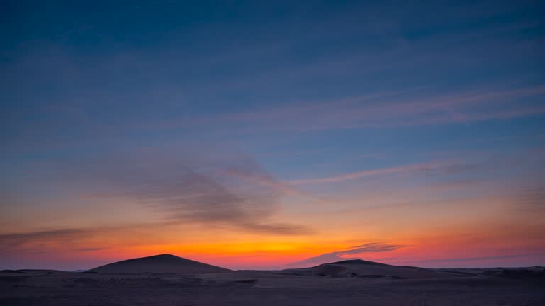 Day to night time lapse in desert sand dune with beautiful clouds.