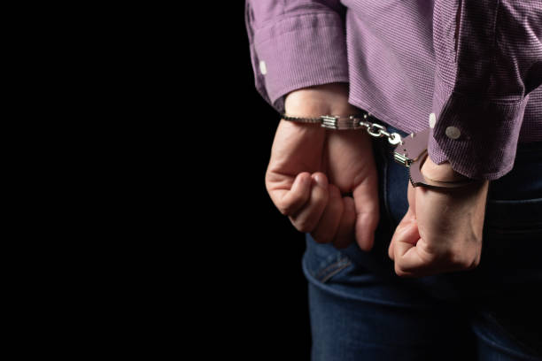istock Arrested man in handcuffs with handcuffed hands behind back in prison 1964991240