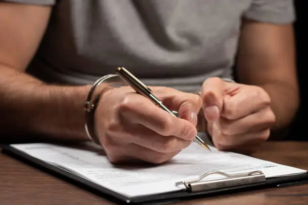 Photo of hand in handcuffs and Tax forms: Tax fraud or Slave to the Taxes. Tax evasion, crime and fraud concept