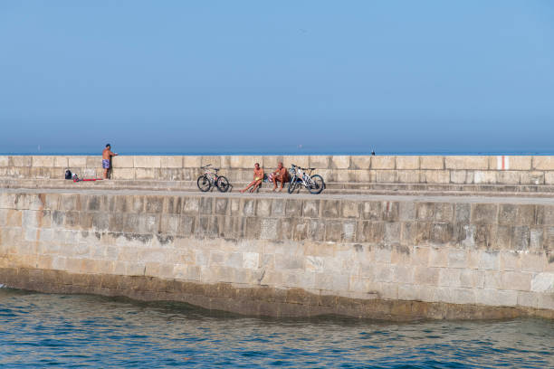 Beach, romance and a couple cycling by the sea, romantic ride during sunset or sunrise. Love, travel and relax in nature, calm bicycle cruise for man and woman. Waves, sand and the sky in background.