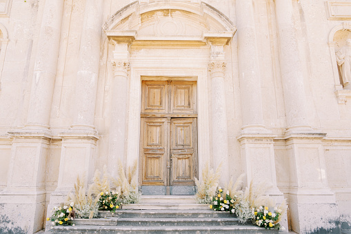 Bouquets of flowers stand on the steps of an ancient church. High quality photo