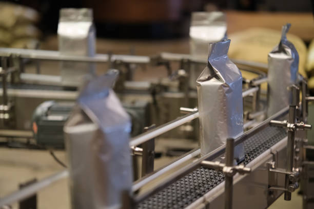 roasted coffee beans in package on conveyor belt in factory. Coffee production