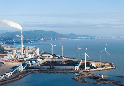 Bird's-eye view of coal power plants and wind turbines by the sea