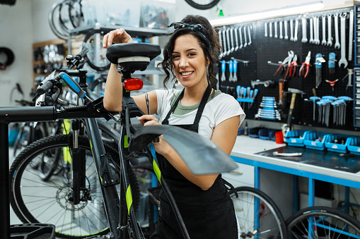 Young female bicycle mechanic working on a customer's bicycle