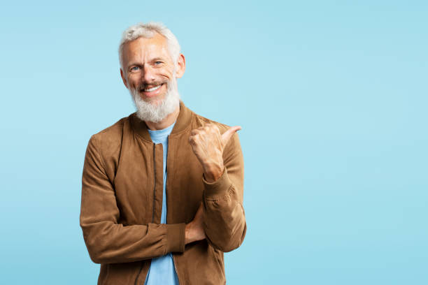 istock Smiling handsome man, bearded hipster isolated on blue background, pointing finger on copy space 1965064822