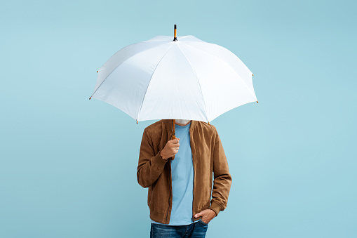 Stylish man holding white stylish umbrella isolated on blue background