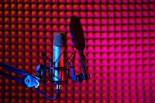 istock Professional studio microphone against acoustic foam panel background in neon light 1965073317