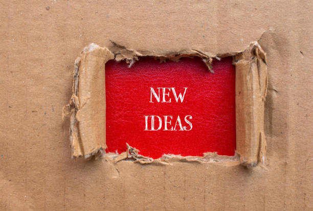 istock New ideas lettering on ripped cardboard paper with red background 1965074237