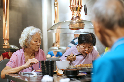 Asian senior family dining outside in restaurant for barbeque