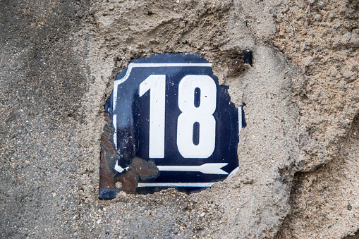 Weathered grunge square metal enameled plate of number of street address with number 18