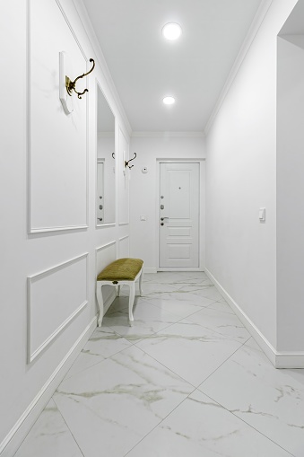 White entrance hall interior with wooden banquette with gold top.