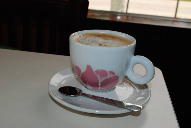 istock Coffee in a white cup on a saucer with spoon on a table by the window. 1965089386