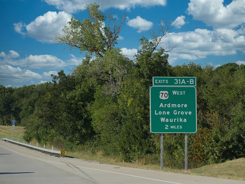 Roadside sign along Interstate 35 showing distance to Ardmore, Lone Grove and Waurika in Oklahoma.