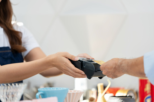 Technology seamlessly intertwines with daily rituals. The focus is on the delicate hand of the customer, wielding her credit card like a key to a world of convenience. With a simple tap, she embraces the speed and security of contactless payment, a testament to the fusion of style and efficiency in the modern age.