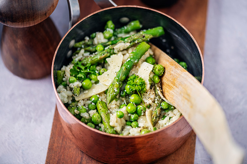 A classic spring time recipe of fresh asparagus and pea risotto. Colour, horizontal format with a high angle view looking into the saucepan.