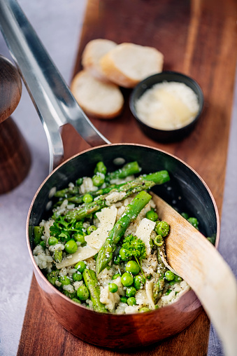 A classic spring time recipe of fresh asparagus and pea risotto. Colour, vertical format with a high angle view looking into the saucepan.