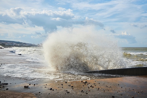 A storm and splashes of waves on the shore of the sea or ocean. The impact of water on the shore