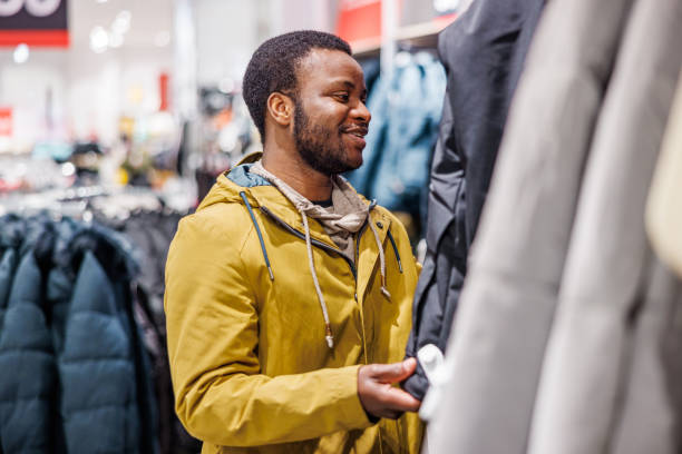 istock Smiling man chooses jacket in boutique 1965116375