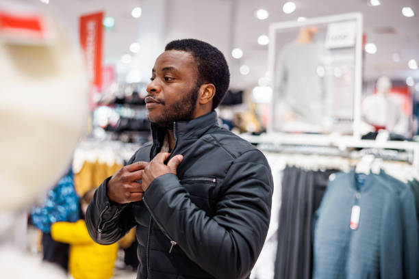 Young man tries new black jacket in boutique