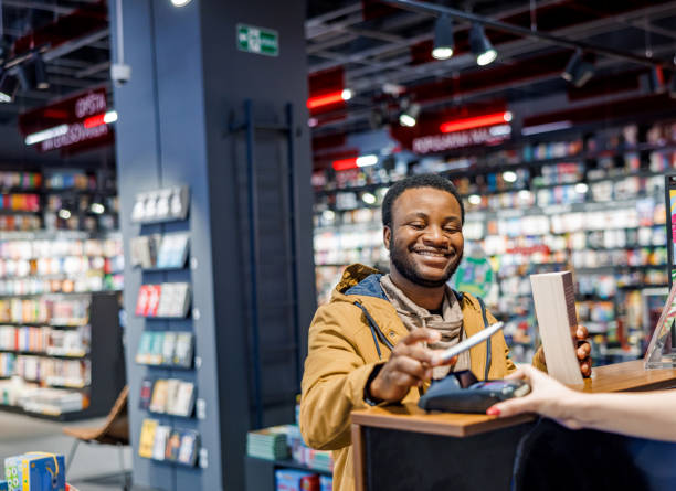 istock Smiling man pays contactless for a book 1965120295