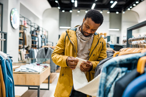 istock Man examines fabric in clothes in boutique 1965121375