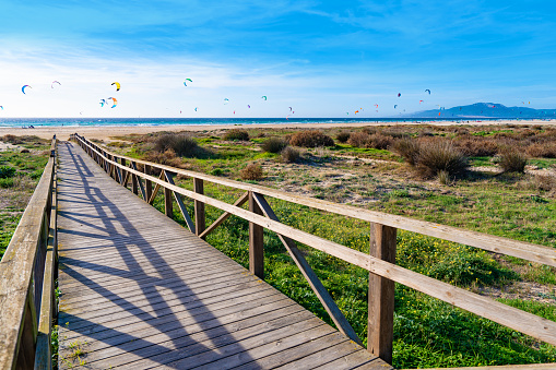 Tarifa beach promenade in Cadiz surf city skyline of Andalusia Spain with lots of kitesurfing kites under blue sunny sky