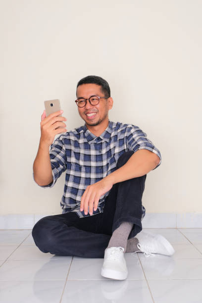 istock A man sitting relax on the floor while looking to his mobile phone with happy expression 1965182894