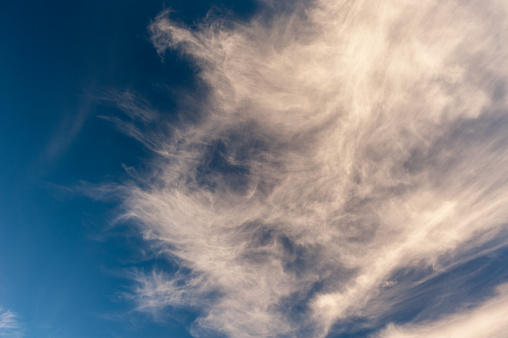 Delicate cirrus clouds feathered across a clear and expansive blue sky.
