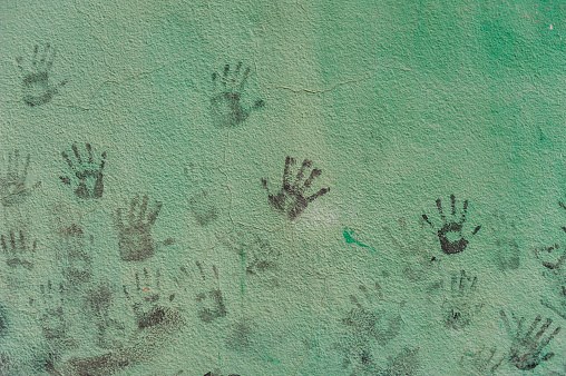 A wall painted green holds the playful memory of children's handprints scattered across its surface.