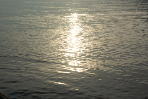 Glittering of evening sunlight reflects on Adriatic sea surface. Photo of the sea with the glare of the sun