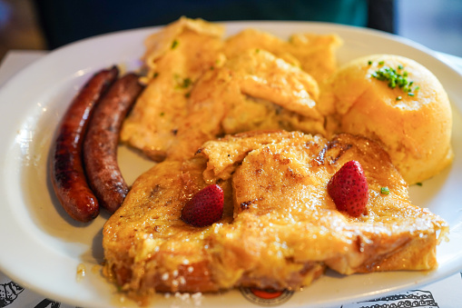 Hearty breakfast plate with French toast, sausage links, and a biscuit.