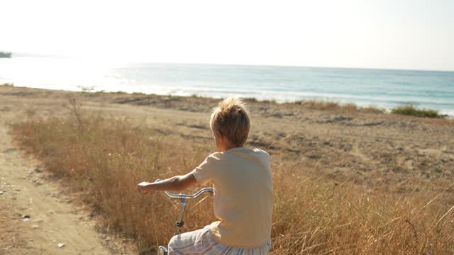 Young boy riding a bicycle by the sea