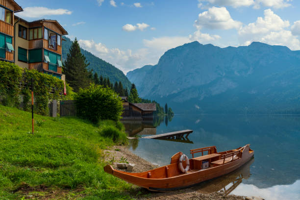 Idyllic alpine resort on the mountain lake with crystal clear water, wooden boats and surrounding mountain peaks. Loser, Altaussee, Austria, Europe.