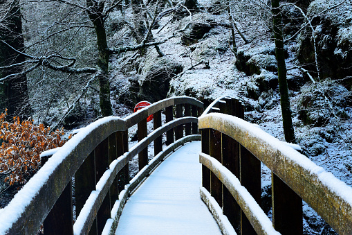 Wooden bridge over a river gorge in Ness forest park covered in undisturbed snow Derry Northern Ireland