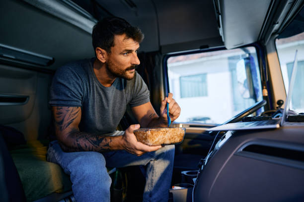 istock Truck driver using laptop while having a lunch in vehicle cabin. 1965302456