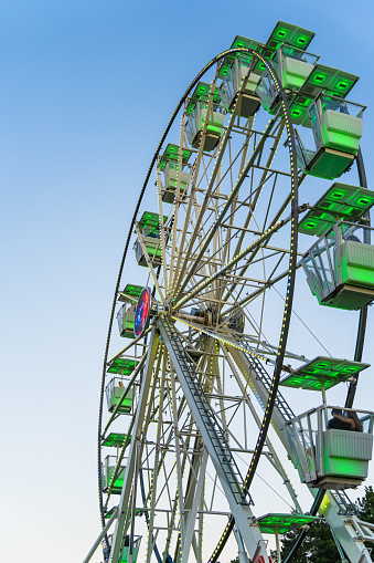 Amusement ride against blue sky. Close up with a white ferris wheel at sunset.