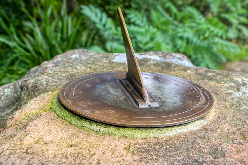 vintage sundial garden metal bronze , casting a shadows on the dial with roman numbers