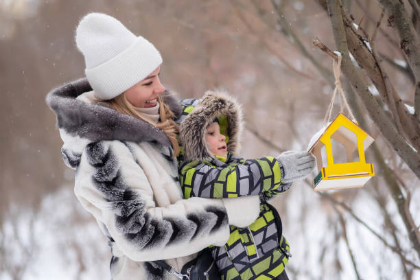 istock mother and son in a winter park feed birds using a feeder 1965396099