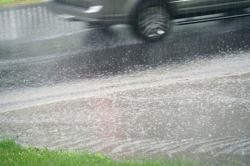 close up on moving car driving through rainy street