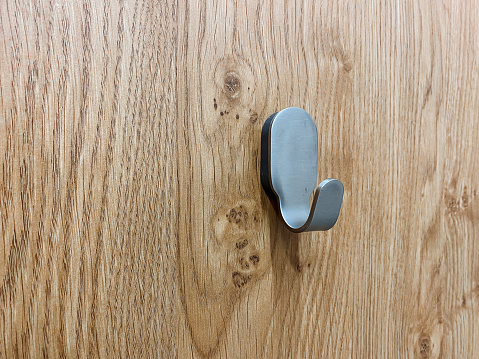 A metal hook hangs on a wooden wall, a hanger in the toilet on the door. High quality photo