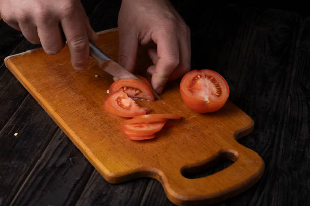 istock Cutting vegetables. Male hands cutting tomatoes on a cutting board. 1965458079