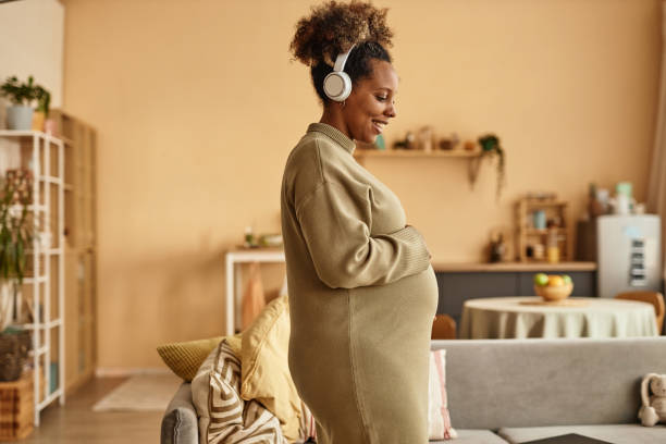 Smiling Expectant Mother in Headphones Listening to Music