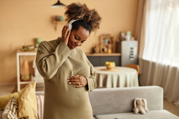 Happy Pregnant Woman Listening to Music at Home