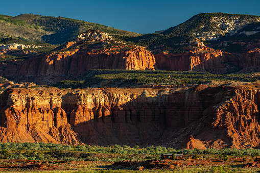 Red rock cliffs of Capitol Reef  national park illuminated by a strong sunlight in Utah early in the morning.